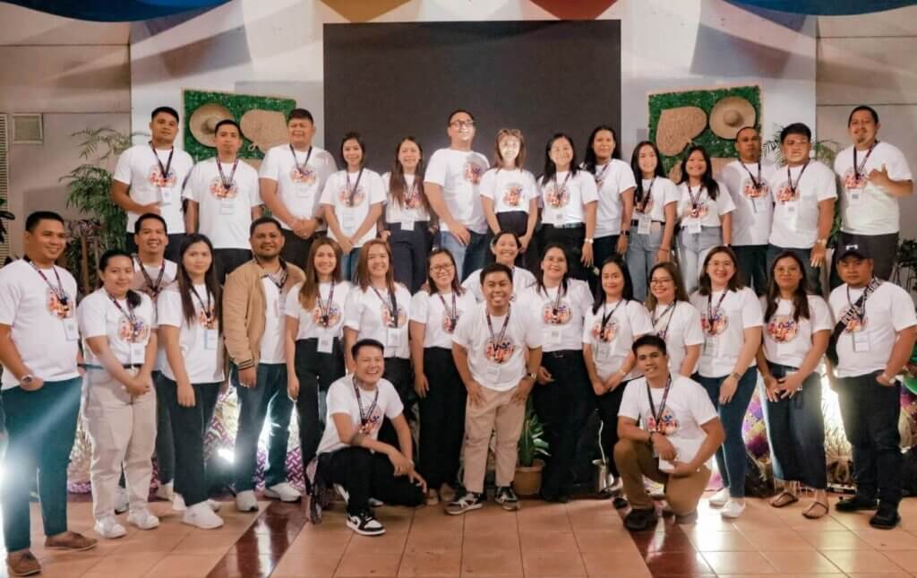 A group of people wearing matching white t-shirts pose for a group photo.