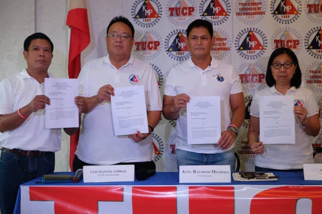 Four TUCP representatives hold documents at a minimum wage press conference.