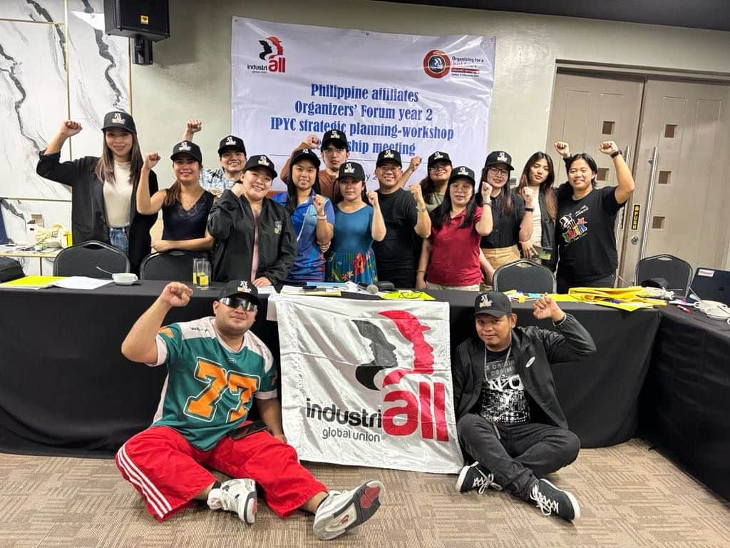 A group of young ALU members with IndustriALL, raising their fists in solidarity at a workshop.