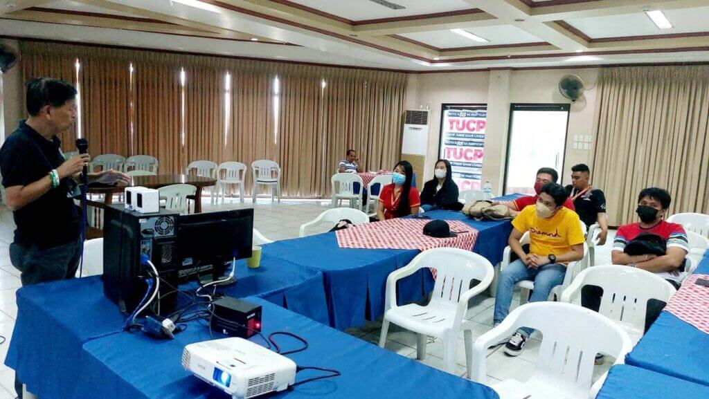 A speaker presents to an audience in a meeting room.