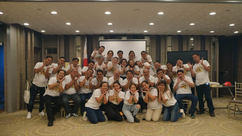 A large group of people wearing matching shirts pose for a photo at Hackathon Tacloban.