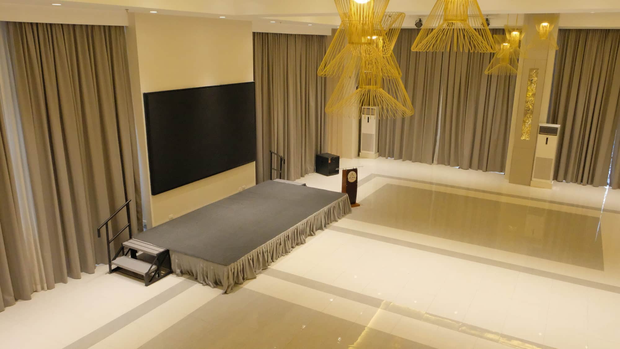ALU Hotel, Cubao - A function hall with a stage, large screen, podium, and modern light fixtures.