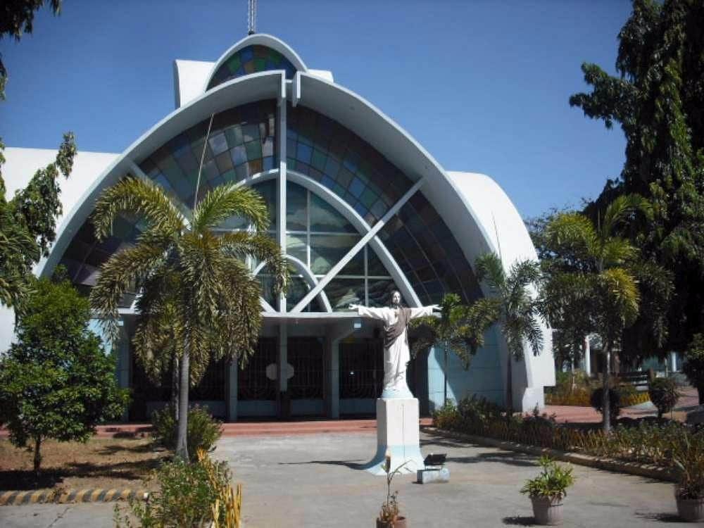 The St. Joseph the Worker Chapel with a statue in front, surrounded by palm trees.