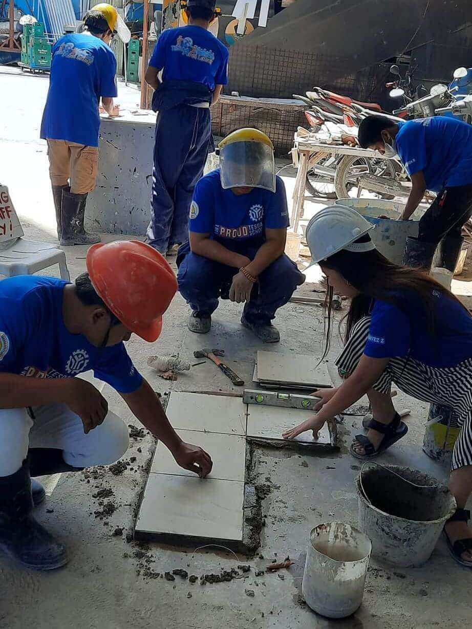 ALU Workers' Training Center - Workers wearing safety gear training in tiling at a training center.